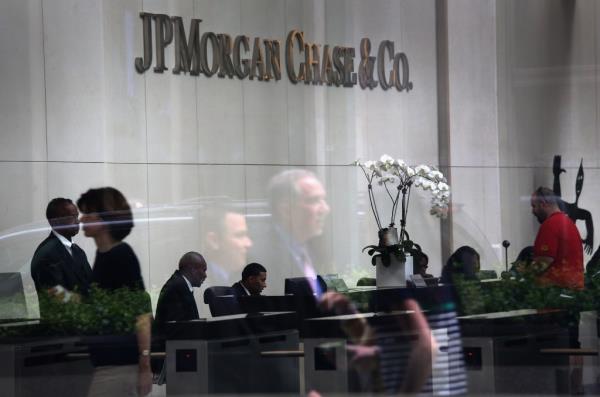 People reflected in the window of JPMorgan Chase headquarters on Park Avenue, midtown Manhattan, New York City on July 13, 2012