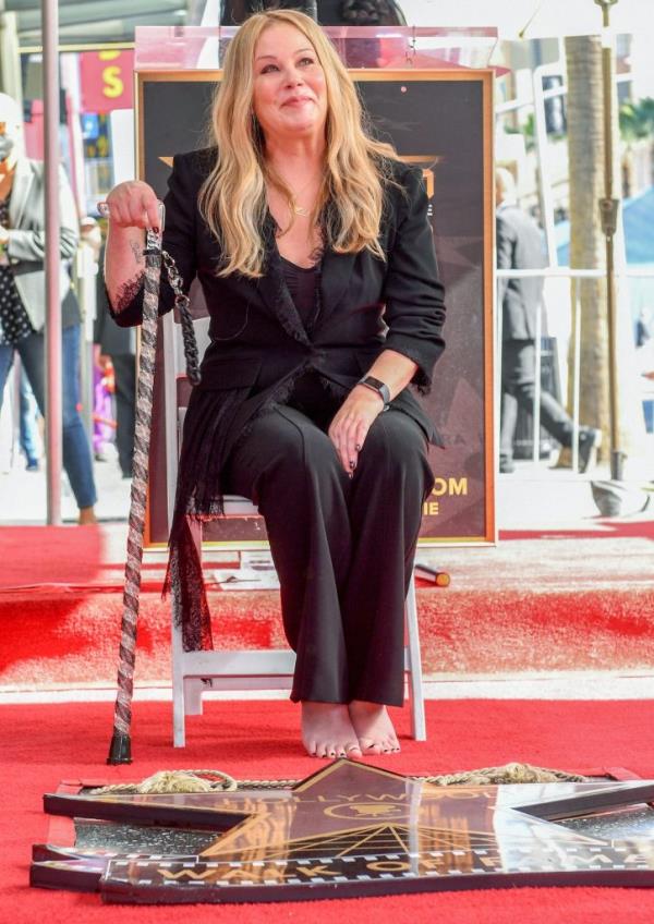 Christina Applegate sitting on a chair with a cane during her Hollywood Walk of Fame star ceremony