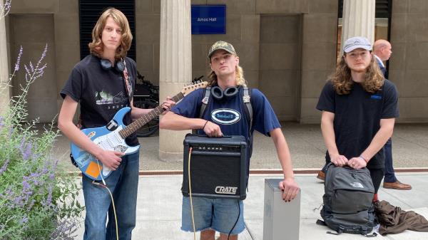 Luke S. (left) holds his electric guitar and friends hold an amp in the freshman quad at University of Pittsburgh.