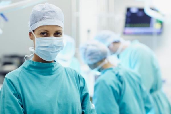 Portrait of co<em></em>nfident female surgeon with colleagues working in operating room