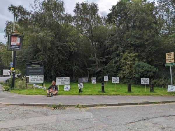 Protesting placards line the grass at the top of the track