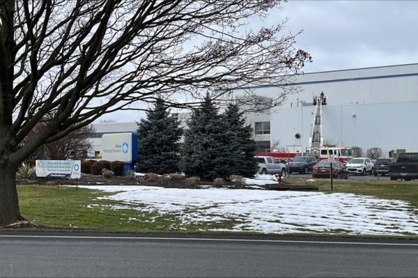 A white building can be seen with a carpark in front of it and a lawn sprinkled with snow