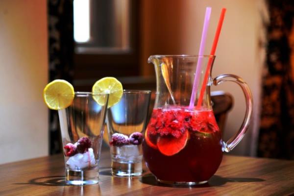 Homemade raspberry lemo<em></em>nade in a bottle and glasses with ice on a white table