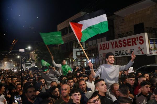 Palestinian priso<em></em>ners (wearing grey jumpers) that were released from the Israeli Ofer military facility in exchange for hostages freed by Hamas in Gaza, wave flags and chant slogans as they are paraded in Baytunia in the occupied West Bank on November 24, 2023.