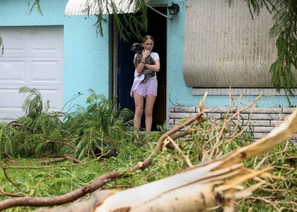12-year-old girl, Mallory Tollett, comforting her dog Maggie amidst the wreckage of her family's property caused by a suspected tornado and Hurricane Milton