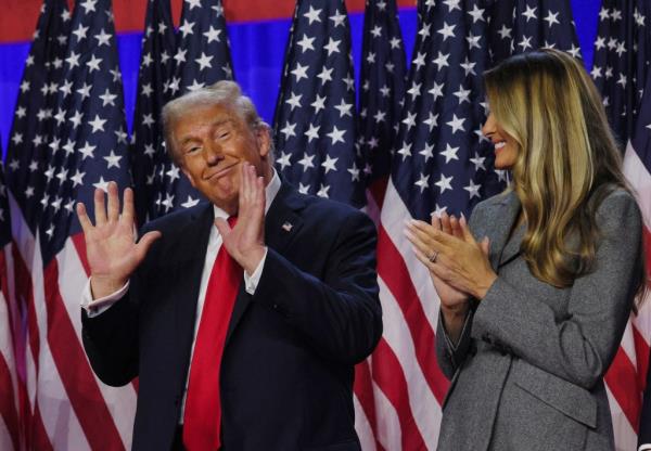 Do<em></em>nald Trump gestures with both hands raised as Melania Trump applauds at Palm Beach election night event on Nov. 6, 2024.