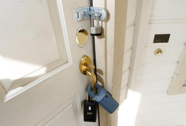 Padlock and real estate agent key lock boxes on the front door of a foreclosed home in Antioch, California
