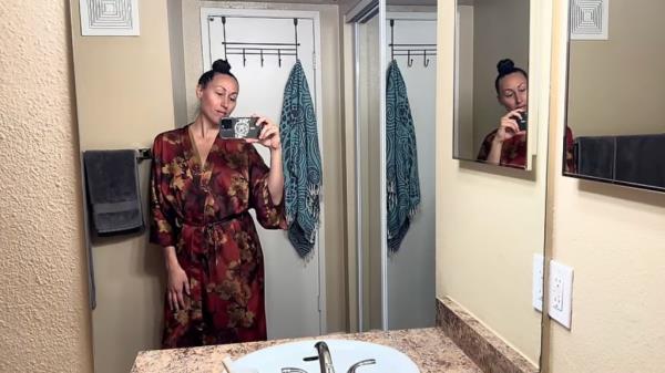 A woman taking a selfie in a bathroom in San Diego wher<em></em>e she lives a minimalist lifestyle and saves money