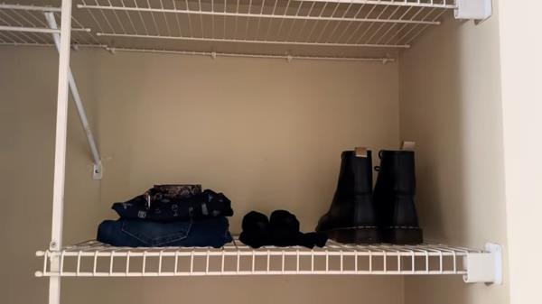 A minimalist's shelf featuring a few pairs of shoes and clothes