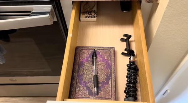 A drawer with a book and pen, symbolizing minimalistic living in an expensive city.