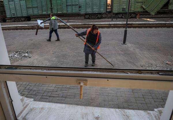 Workers clean up an area of the train station following the attack in Kherson, Ukraine on Dec. 27, 2023.