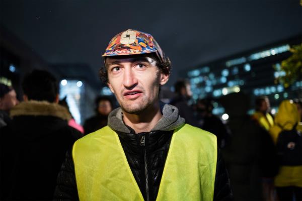 Person wearing bright yellow vest at a nighttime demonstration