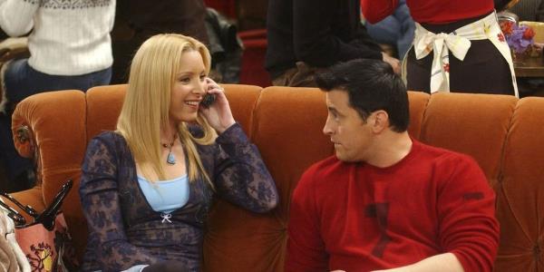 Phoebe talking on the phone and Joey staring at her on the couch in Central Perk in Friends